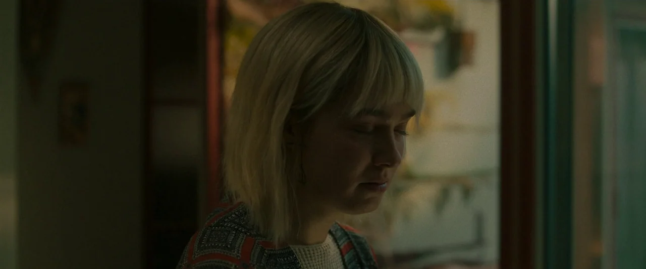 After Yang (2021) movie still: closeup — A close portrait showing a young woman with blonde hair inside a room. She stands with her eyes closed,…
