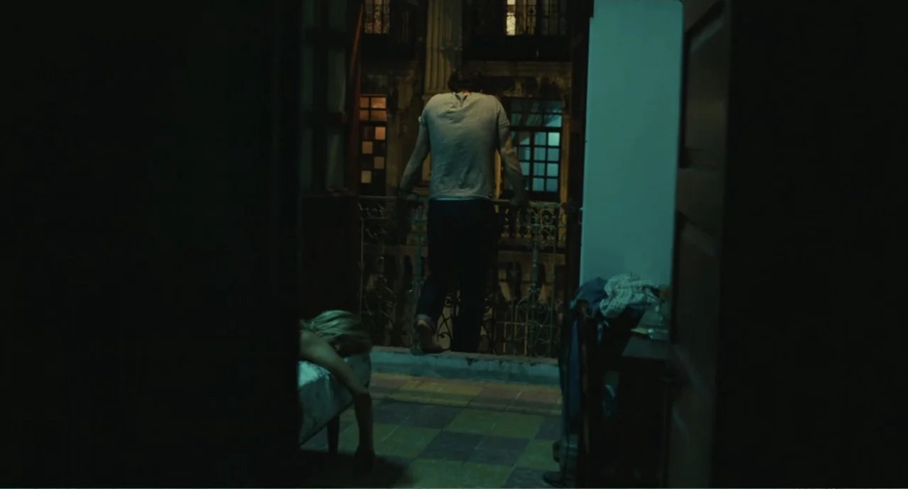 Bad Boys: A True Story (2003) movie still: fullbody — An interior room opens onto a balcony overlooking a dimly lit urban building facade. A man…