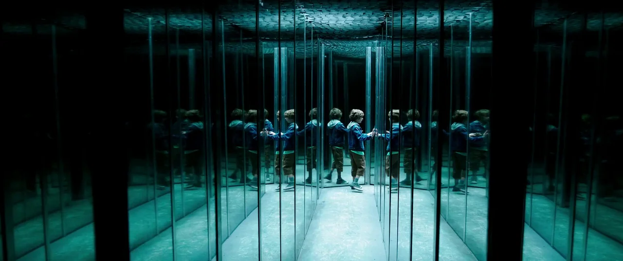 It Chapter Two (2019) movie still: fullbody — A narrow corridor features multiple tall, vertical mirrors reflecting a single child repeatedly. The…