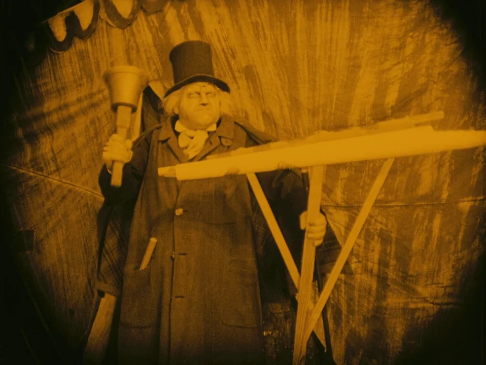 The Cabinet of Dr. Caligari (1920) movie still: medium — A man stands in front of a textured backdrop under a circular vignette. He holds a metal…