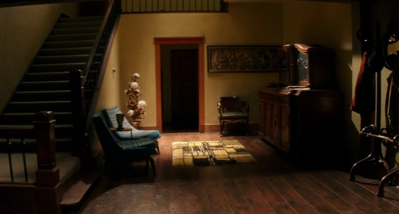 Ouija: Origin of Evil (2016) movie still: wide — A residential foyer features dark wood flooring, a staircase, and mid-century modern furniture…
