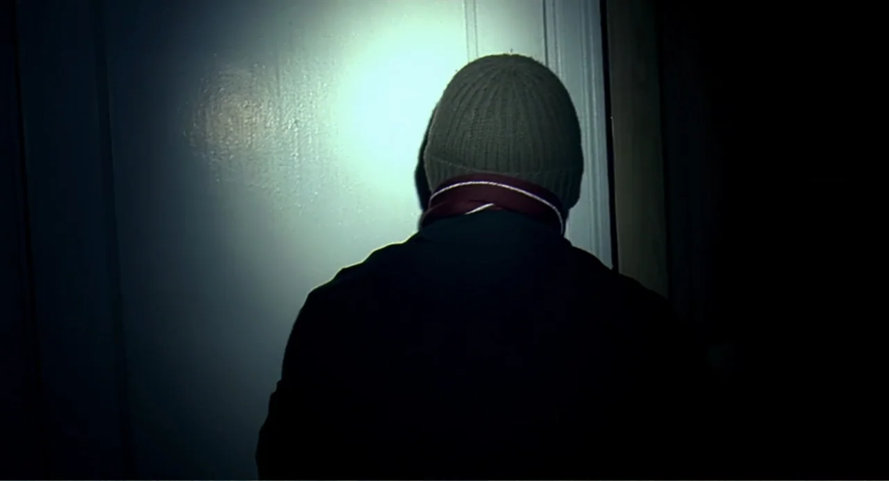 Eternal Sunshine of the Spotless Mind (2004) movie still: medium — A dark, confined indoor space with a single bright light focused on a wall. A man…