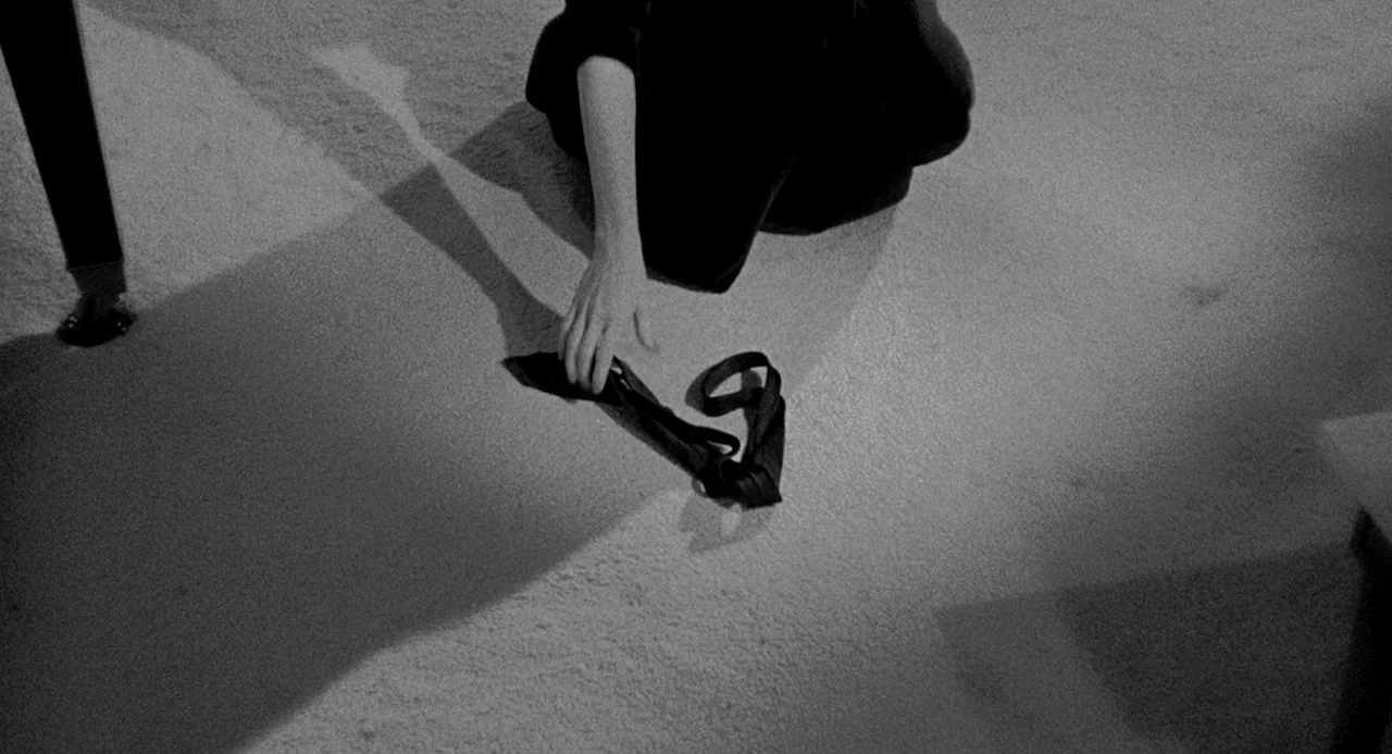 Murder By Contract (1958) movie still: medium — A dark, carpeted floor is illuminated by a harsh, singular light source. A person in dark clothing…