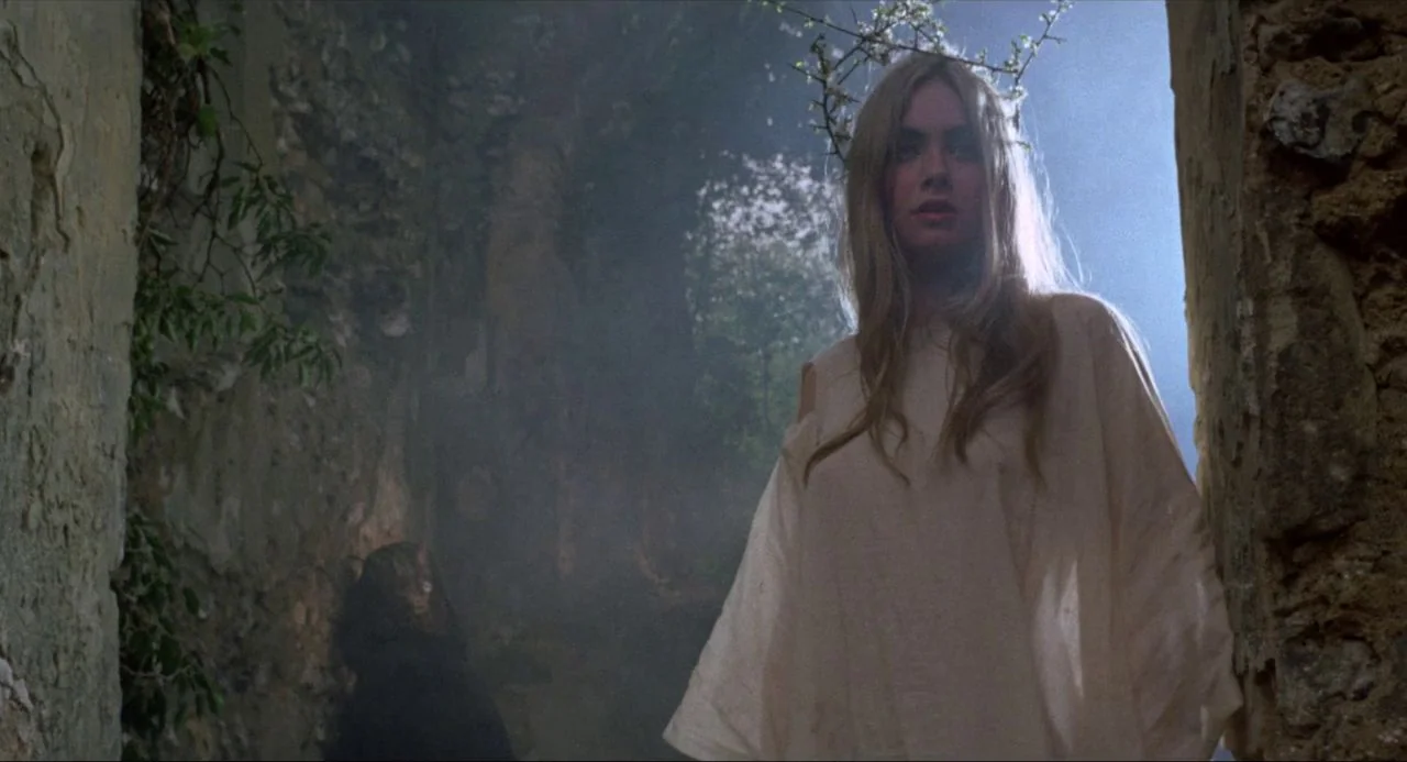 The Blood on Satan’s Claw (1971) movie still: medium — A woman stands in the crumbling stone doorway of ancient ruins filled with haze. She wears a…