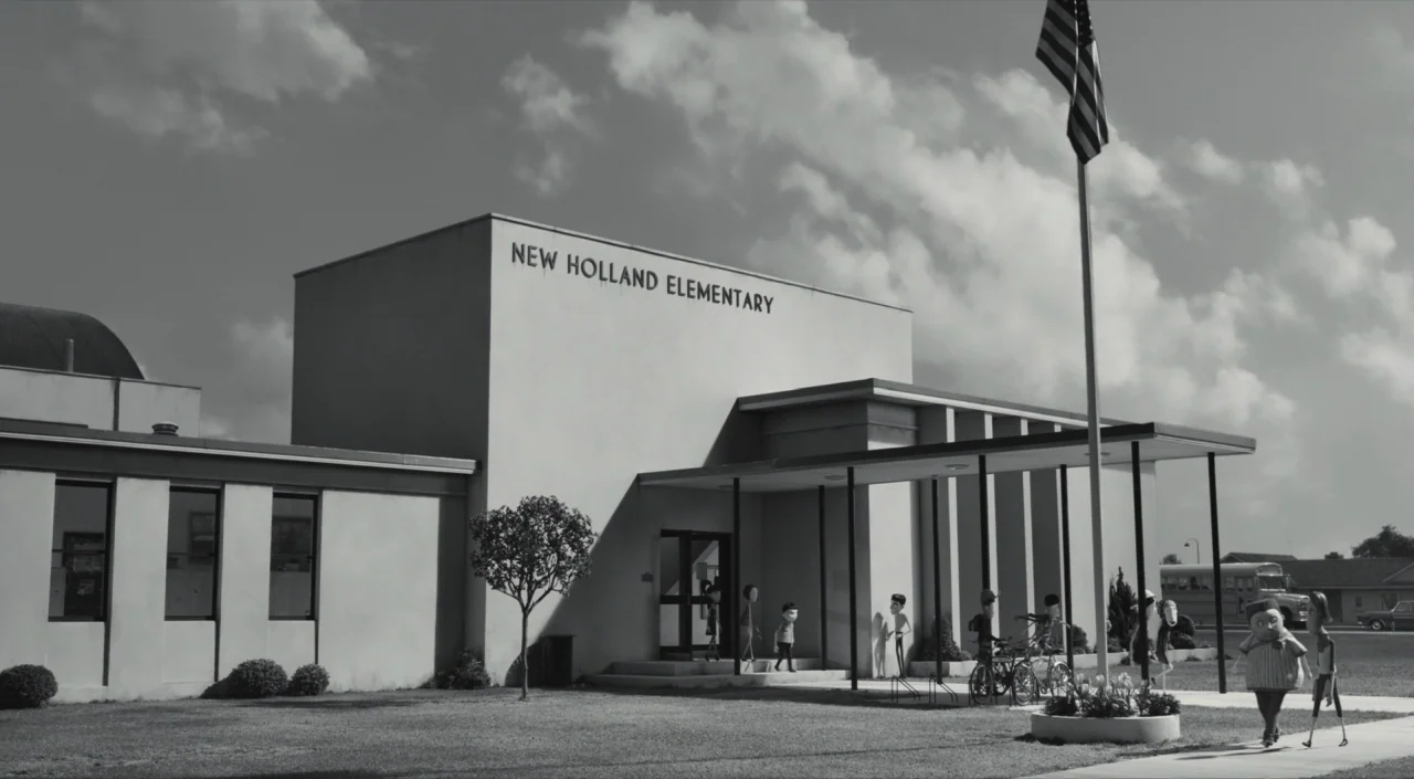 Frankenweenie (2012) movie still: wide — A modernist elementary school building stands under a bright sky with scattered clouds. Several small…