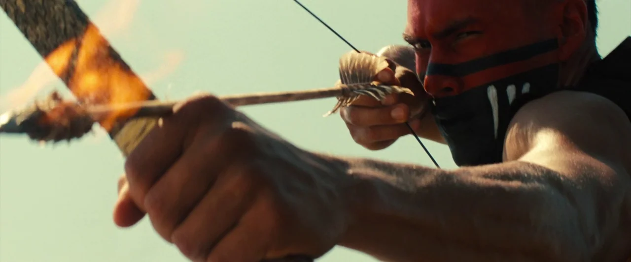 The Magnificent Seven (2016) (2016) movie still: closeup — An archer draws a fire-tipped arrow against a pale, open sky background. The man has war…