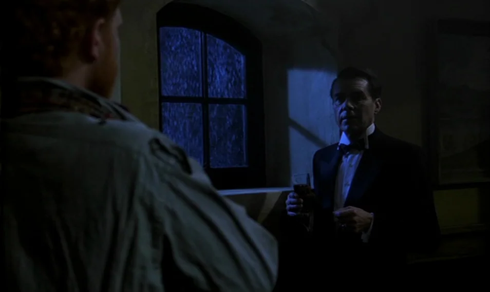 Despair (1978) movie still: medium — A dimly lit interior room at night features a man in a tuxedo.