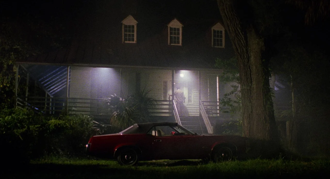 City of the Living Dead (1980) movie still: wide — A two-story white house with a wrap-around porch sits in the dark night. A vintage red…
