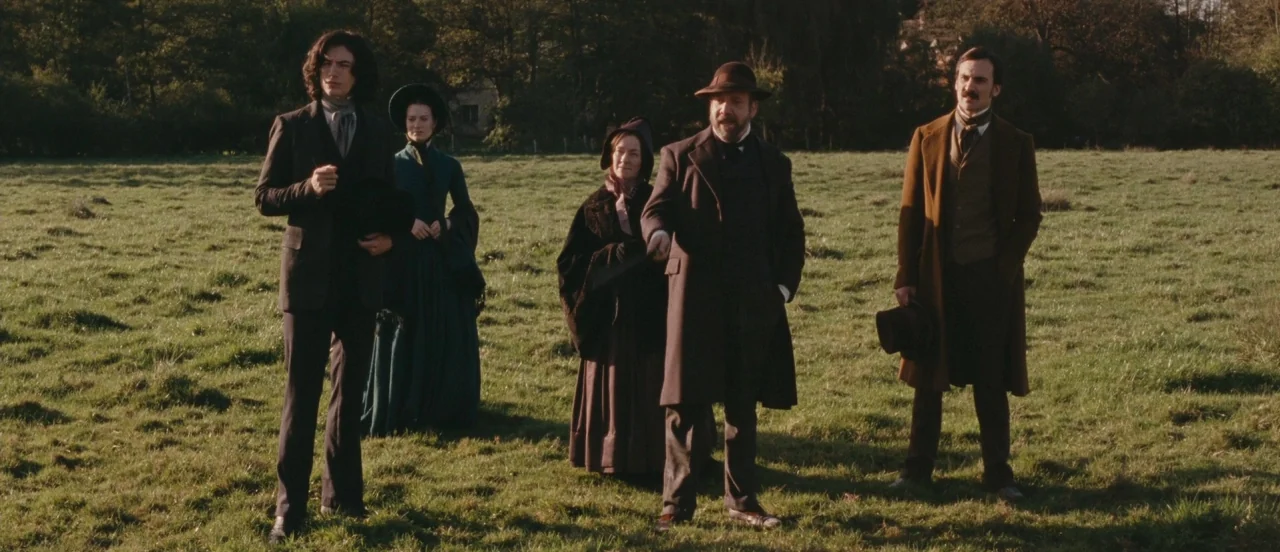 Madame Bovary movie still: fullbody — Five figures in Victorian-era clothing stand together in a wide grassy meadow. They face off-camera to the…