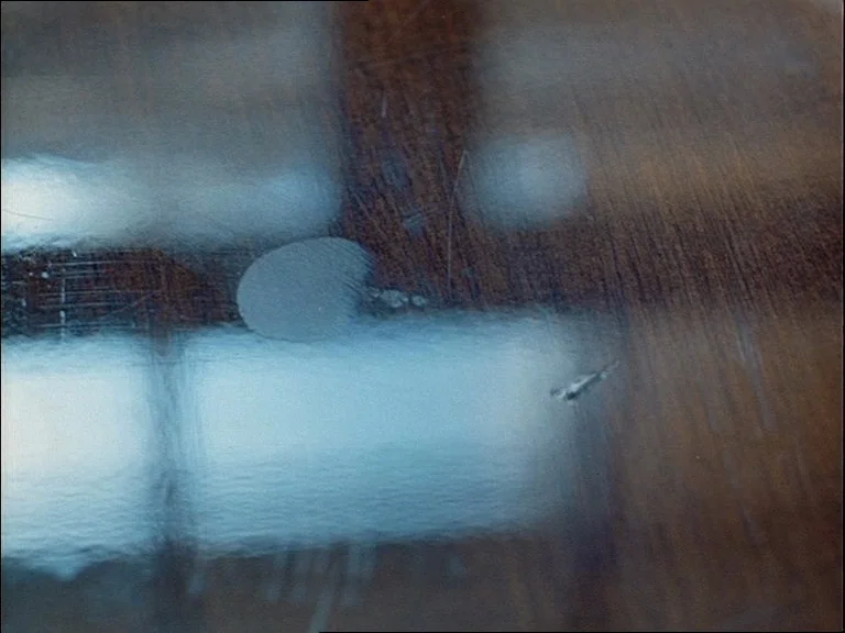 Mirror (Зеркало, Zerkalo) (1975) movie still: closeup — A dark wooden surface displays visible scratches and a prominent smooth fingerprint smudge.…