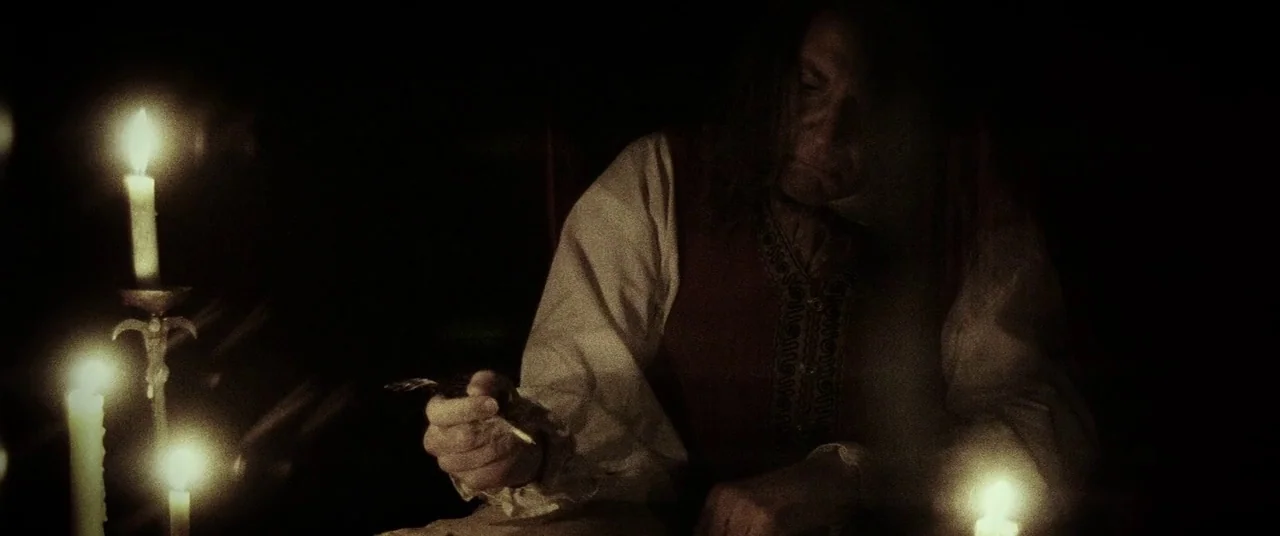 Lords Of Salem (2013) movie still: medium — A dark study is dimly illuminated by several candles arranged on a wooden table. A man in period…