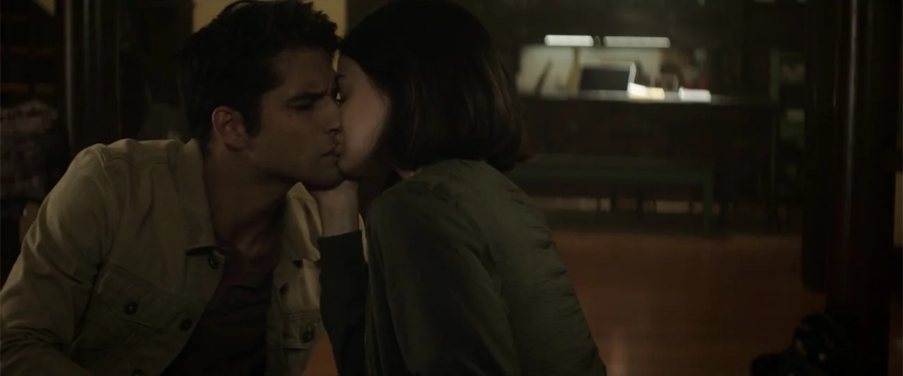 Truth or Dare (2018) movie still: medium — An interior space is dimly lit with furniture visible in the blurred background. A young couple faces…