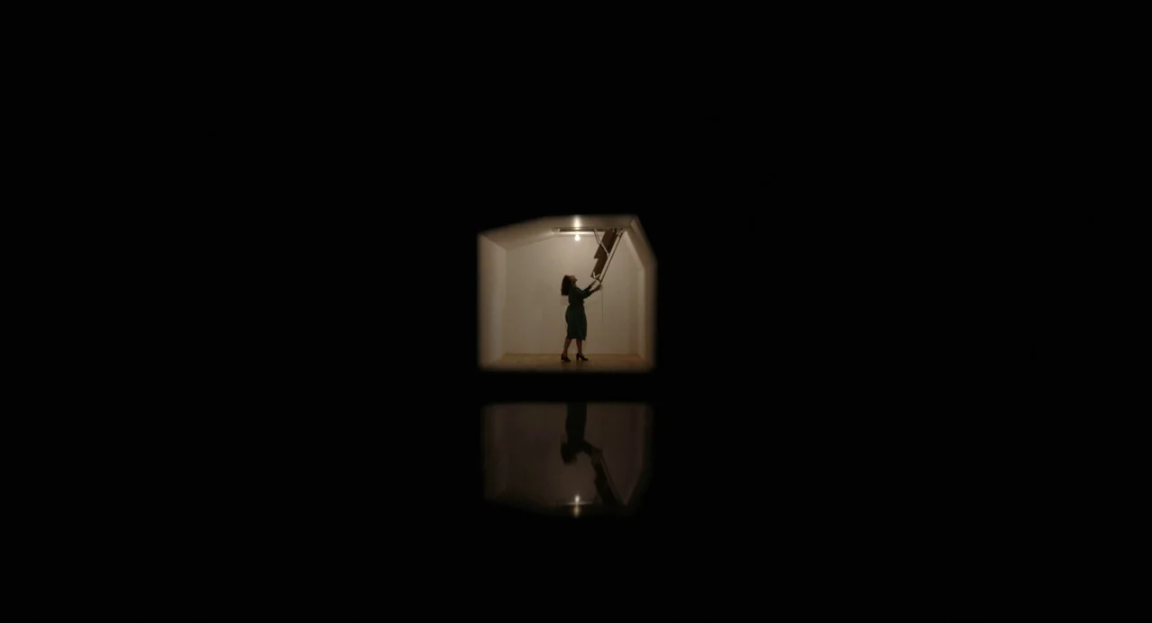 Beau Is Afraid (2023) movie still: wide — A small white box-like structure floats in absolute blackness with a reflective floor surface. A woman…