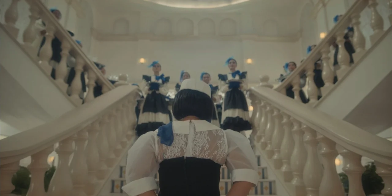 Ten Little Mistresses (2023) movie still: medium — A grand interior staircase features stone balusters and several levels of landings. A woman in a…