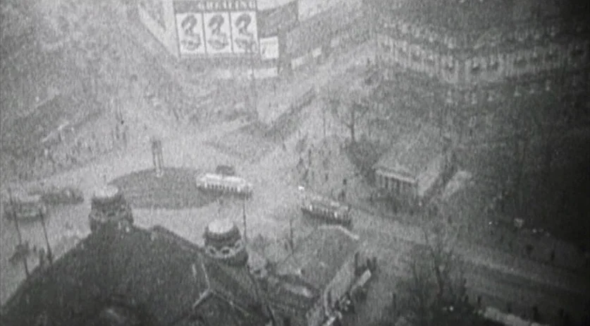 Invincible (2001) movie still: establishing — An overhead view captures a congested European city square with trams and pedestrians moving.…