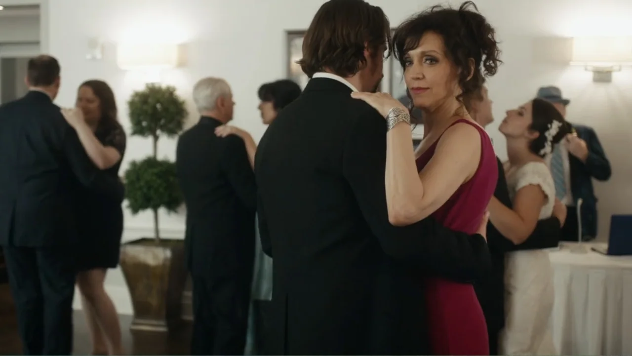 Toss It (2019) movie still: medium — A well-lit indoor reception area with multiple couples dancing on a wooden floor. A woman in a magenta dress…