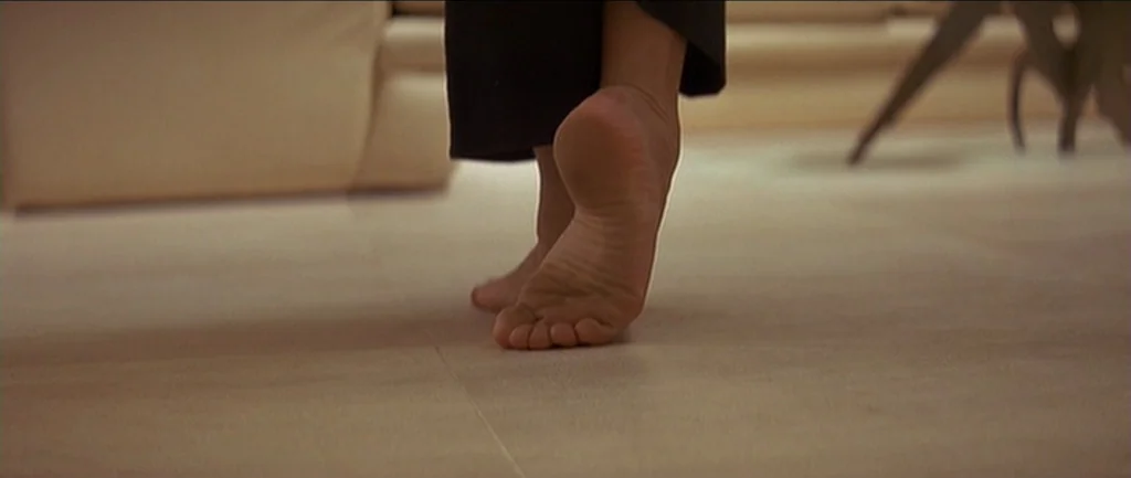 Pulp Fiction (1994) movie still: closeup — A cream-colored tiled floor occupies the interior space. A person's bare foot balances on its toes while…