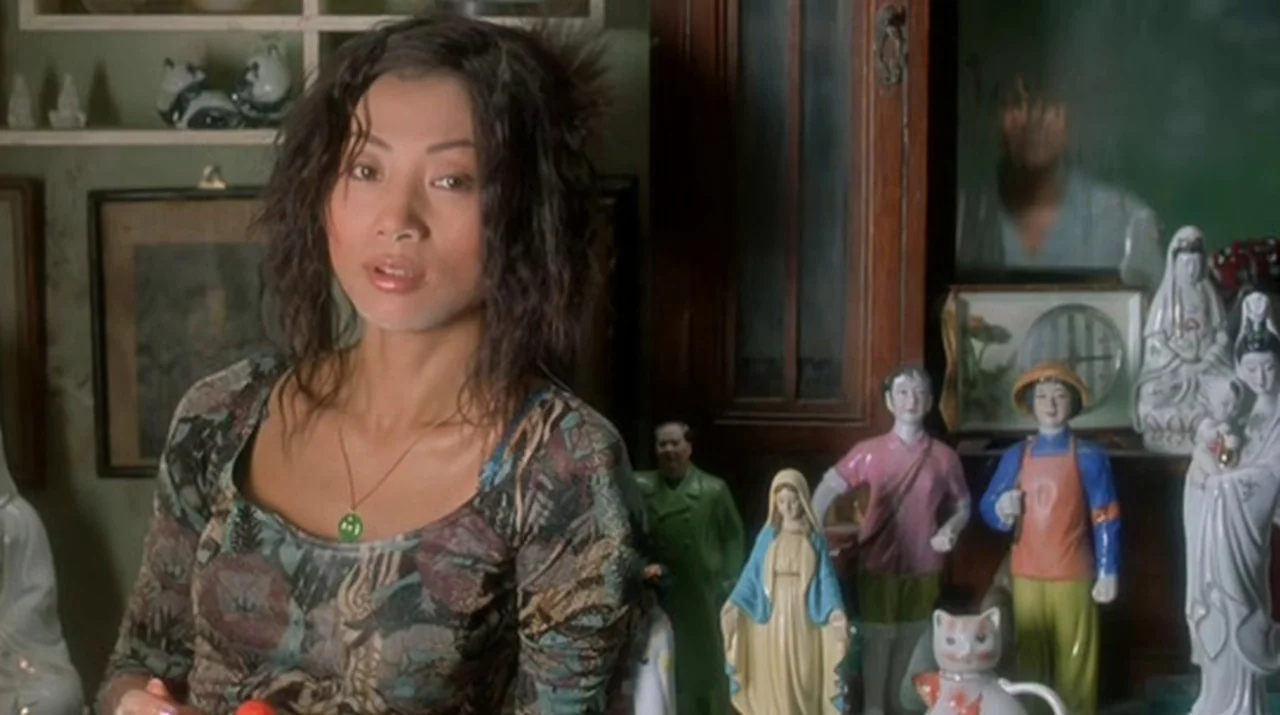 Dumplings (2004) movie still: medium — An interior space is crowded with various porcelain figurines and religious statuary on shelves. A woman with…