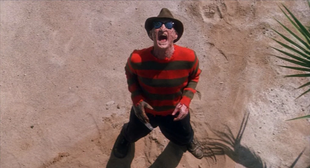 A Nightmare On Elm Street 4: The Dream Master (1988) movie still: fullbody — A figure stands in a clearing of sandy ground under bright daylight…