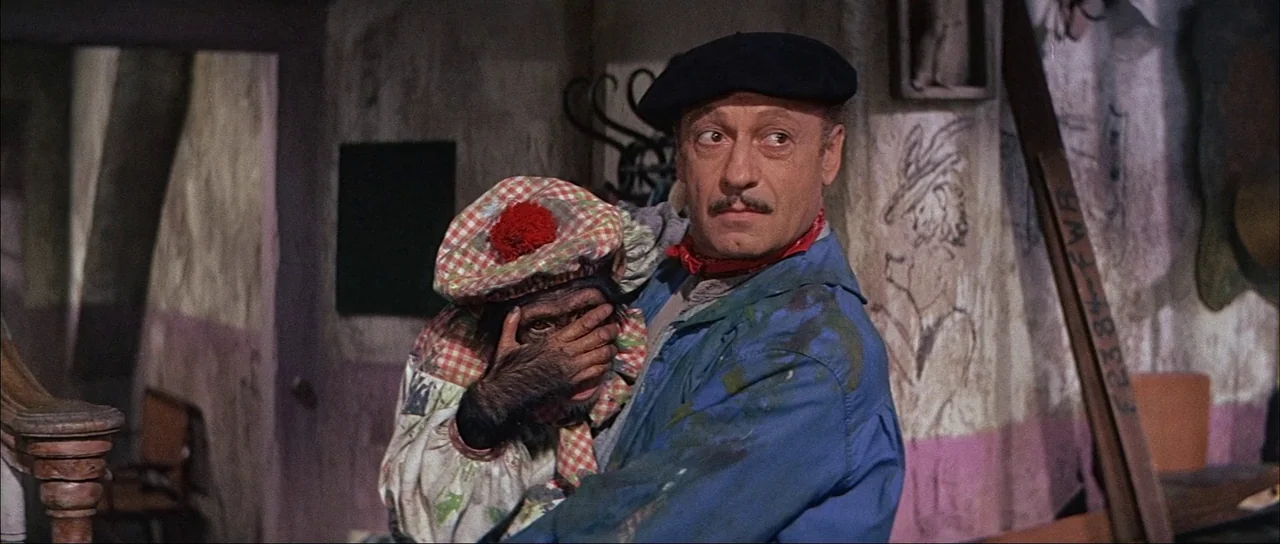 What A Way To Go! (1964) movie still: medium — A cluttered interior space features walls covered with charcoal sketches and faded pink paint. A…