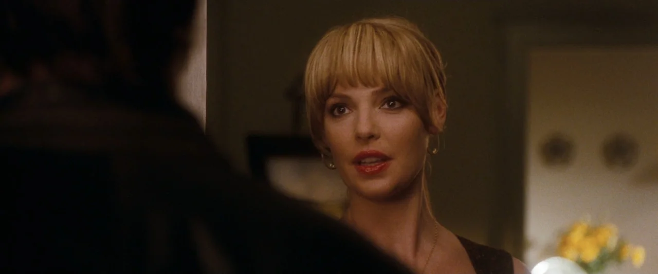 Life As We Know It (2010) movie still: closeup — A dimly lit indoor space with soft-focus background elements including yellow floral arrangements.…