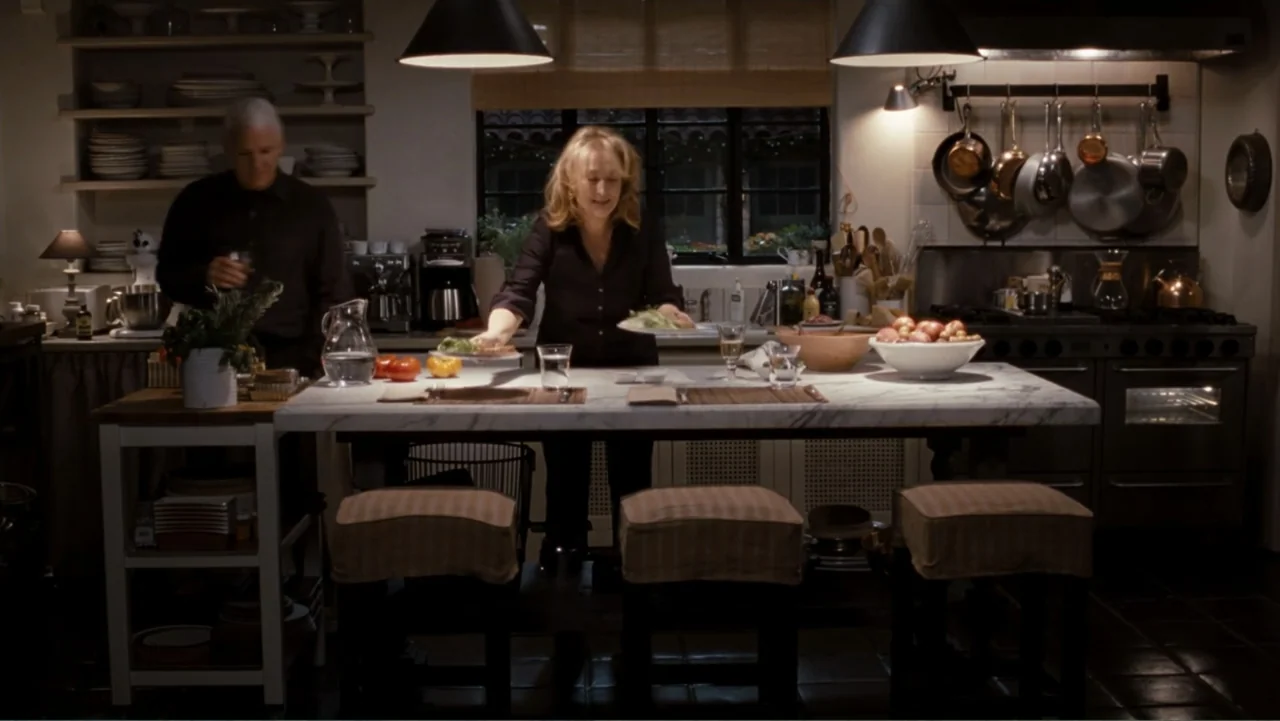 It's Complicated (2009) movie still: medium — A well-equipped kitchen features a large marble-topped island, wooden cabinetry, and hanging copper…