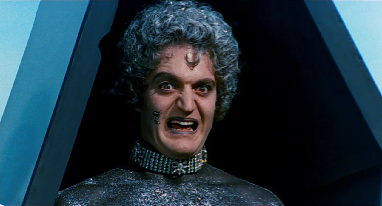 Phantom of the Paradise (1974) movie still: closeup — A dark, cramped interior with sharp geometric metallic structures framing the character. A man…