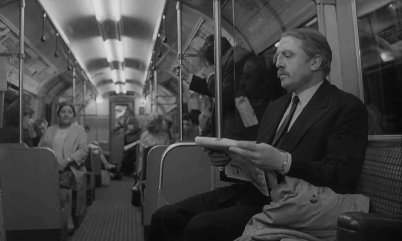 Seance on a Wet Afternoon (1964) movie still: medium — A well-lit subway car interior features rows of seats and central support poles. A man sits…