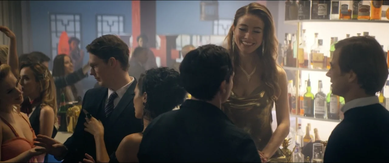 Utopia (2013) movie still: medium — A well-lit bar counter with backlit spirit bottles on glass shelves behind patrons. A woman in a gold dress…