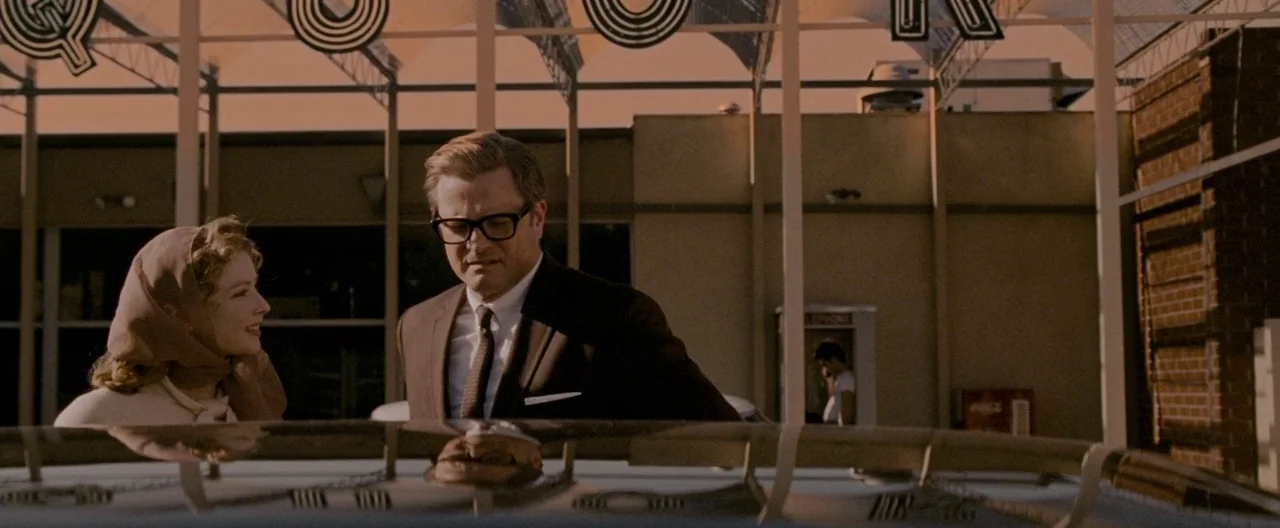 A Single Man (2009) movie still: medium — A vintage 1960s gas station with large block lettering visible under a white roof. A man in glasses and a…