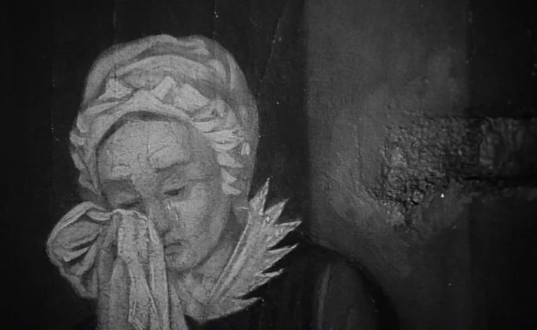 The Cremator (1969) movie still: closeup — A detailed painting of an elderly woman in period clothing occupies the dark frame. She holds a white…