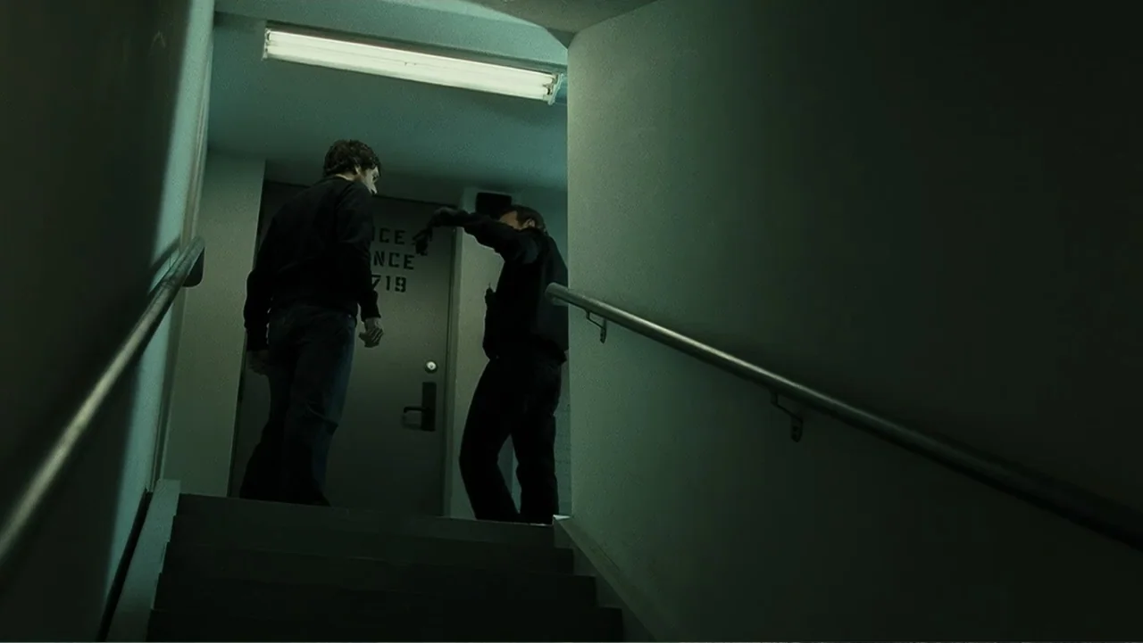 Mr. Brooks (2007) movie still: fullbody — A utilitarian concrete stairwell with a metal access door labeled 719. Two men in dark clothing stand…