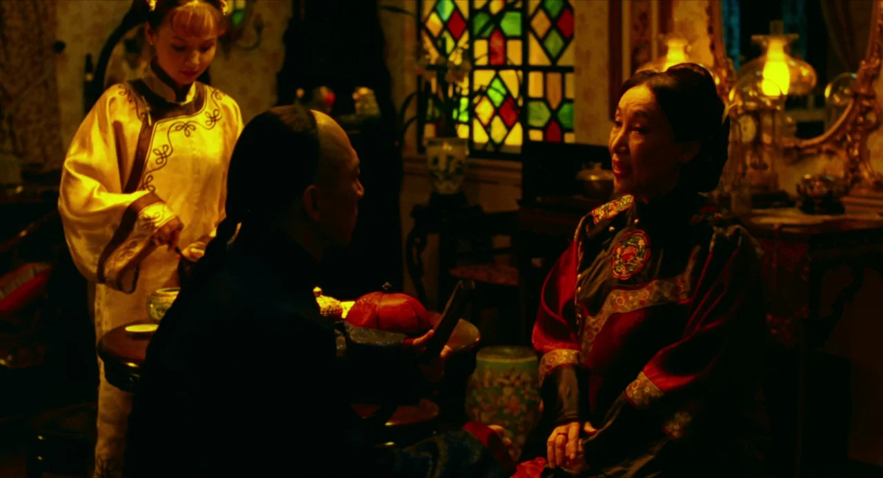 Flowers of Shanghai (1998) movie still: medium — A dimly lit room features ornate wood furniture and a colorful stained glass window. Three people…