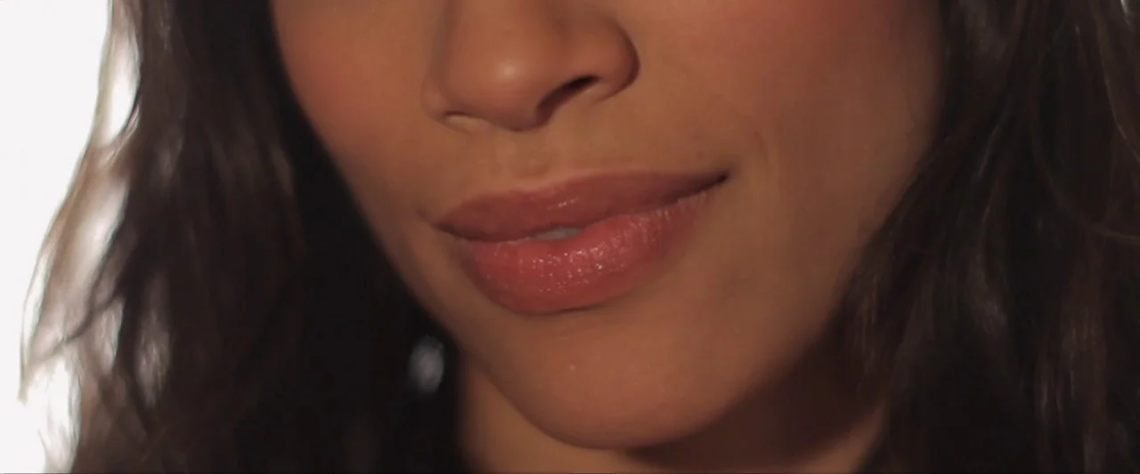 Girl Walks Into a Bar (2011) movie still: closeup — A close-up shot of a woman's lower face in an indistinct indoor setting. The subject displays a…