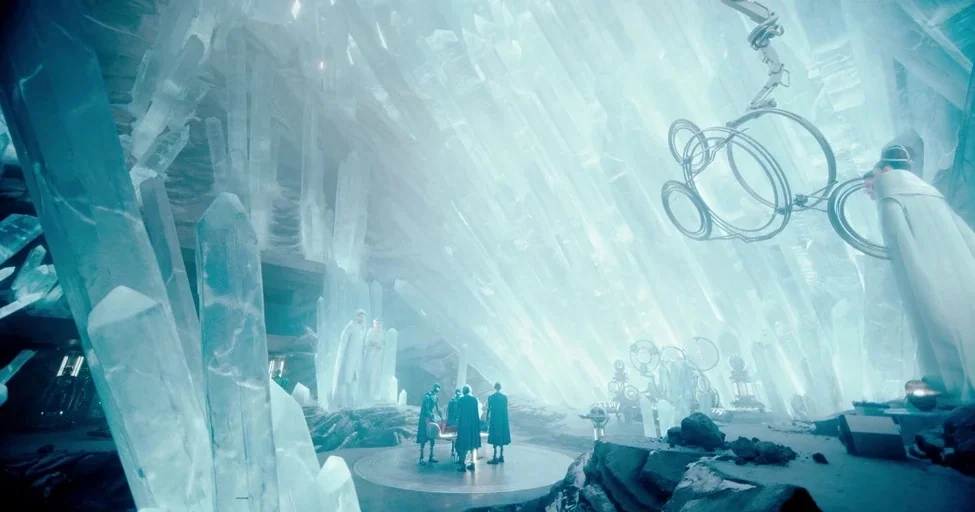 Superman (2025) movie still: wide — A vast interior cavern filled with massive, jagged, translucent light-emitting ice or crystal formations. A…