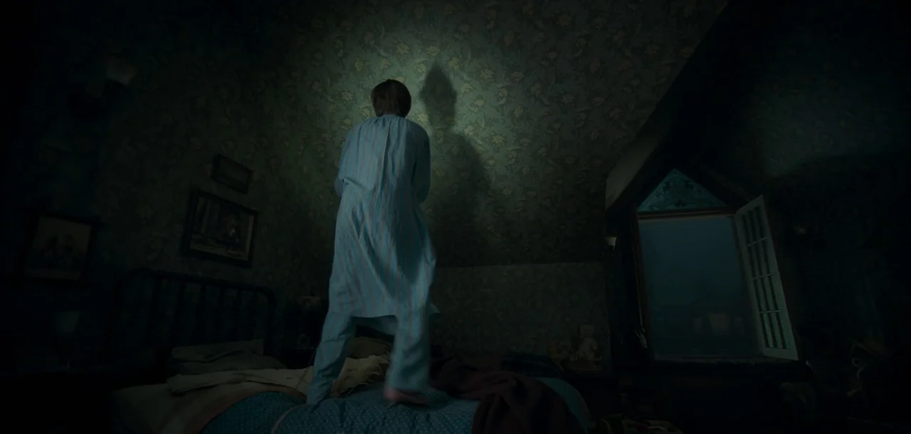 Peter Pan & Wendy (2023) movie still: fullbody — An attic room features dark green floral wallpaper and an open window revealing night. A child in…