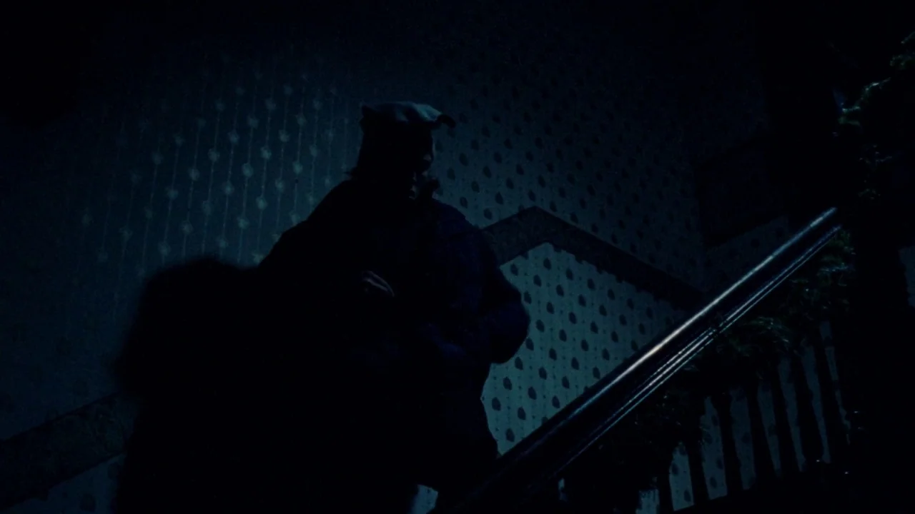 I Am Not a Serial Killer (2016) movie still: medium — A dark, wood-banistered staircase features patterned Victorian-style wallpaper under deep…