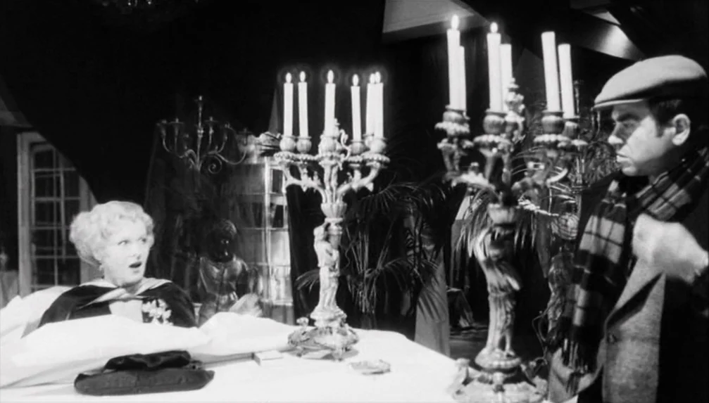 Veronika Voss (1982) movie still: medium — An opulent dining table features ornate silver candelabras and white cloth linens. A blonde woman looks…