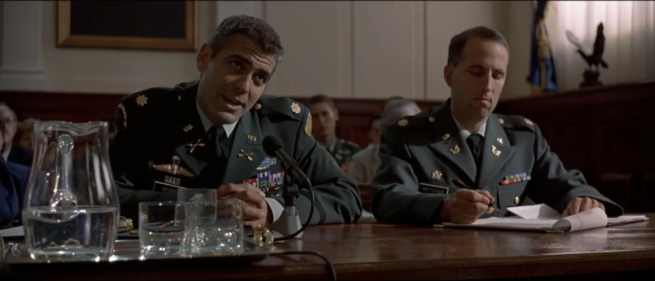 The Peacemaker (1997) movie still: medium — A dark wooden courtroom features two military officers seated at a table during proceedings. The man on…