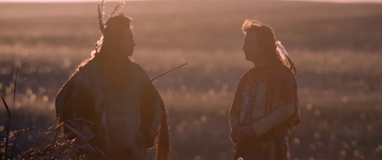 Dances With Wolves (1990) movie still: medium — An open prairie at sunset provides a vast, backlit backdrop for two men meeting. The men stand in…