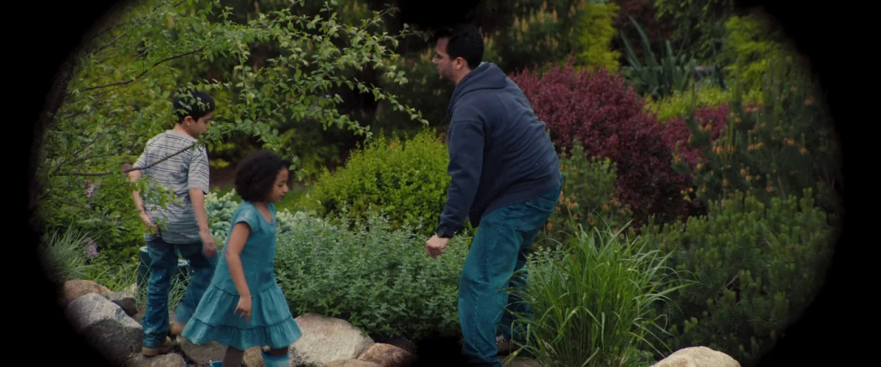 Kiss of the Damned (2012) movie still: fullbody — A lush botanical landscape features varied shrubs, trees, and large stone border rocks. A man…