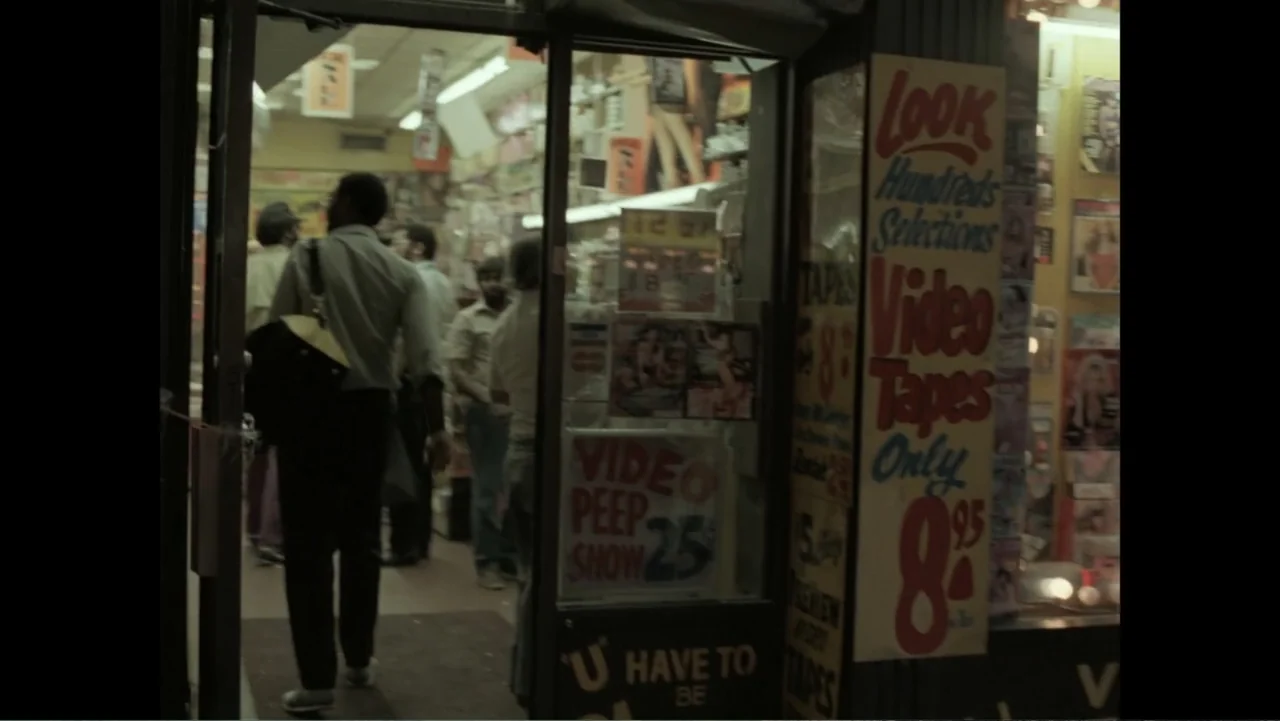Dear Ms.: A Revolution in Print (2025) movie still: medium — A cramped video store entrance displays vintage movie posters and promotional signs on…
