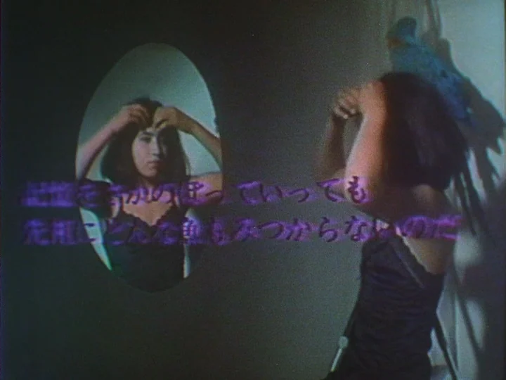 Les Chants de Maldoror (1977) movie still: medium — A dimly lit room contains an oval mirror mounted on a dark wall. A woman in a black camisole…