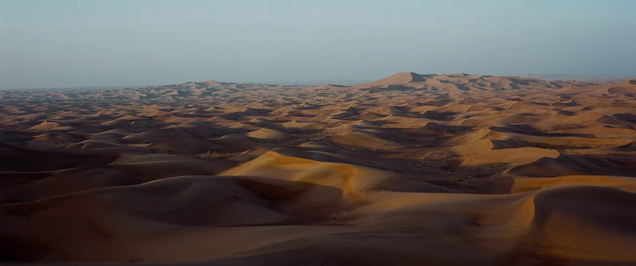 Mission: Impossible – Ghost Protocol (2011) movie still: establishing — A vast, rolling desert landscape stretches toward the horizon under a hazy…