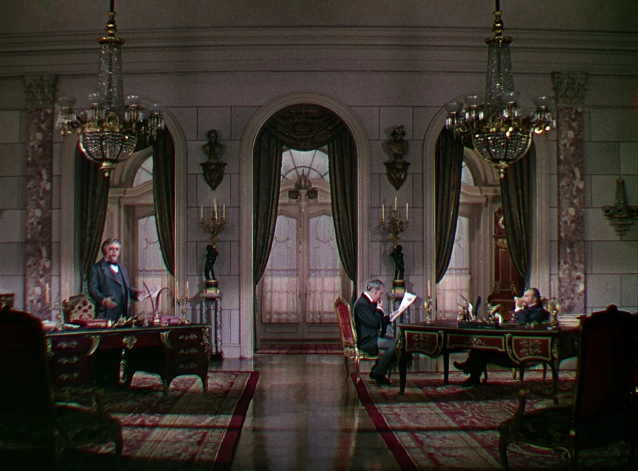 Phantom of the Opera (1943) movie still: wide — A spacious, formal study features ornate wood desks, crystal chandeliers, and arched window alcoves.…
