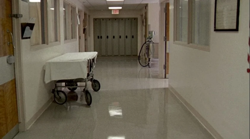 The House Of The Devil (2009) movie still: establishing — An empty institutional hallway features cream walls and a highly polished linoleum floor.…