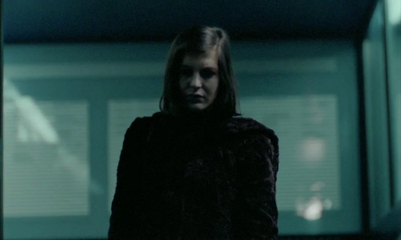The Lost Honour of Katharina Blum (1975) movie still: medium — A dark, dimly lit office interior at night with closed venetian blinds in background.…