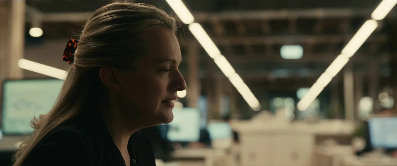The Invisible Man (2020) (2020) movie still: closeup — A modern open-plan workplace features rows of desks and backlit computer monitors in…