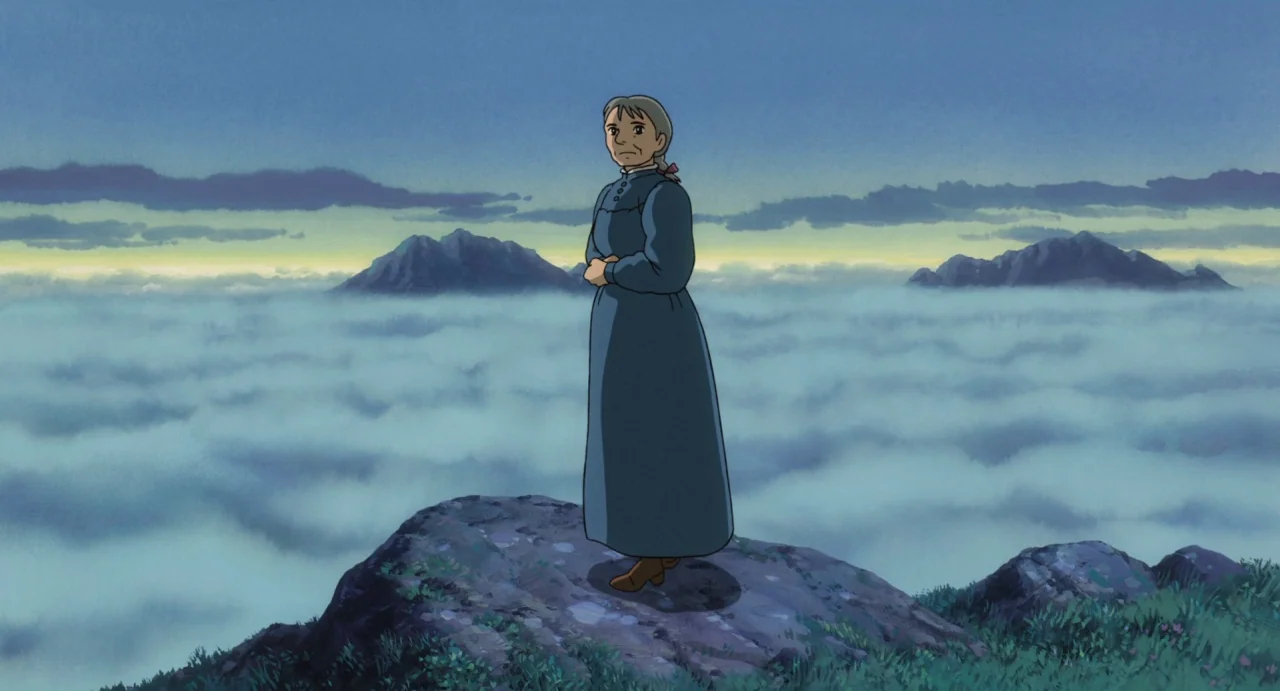 Howl’s Moving Castle (2004) movie still: fullbody — A high rocky mountain summit rises above a dense layer of rolling white clouds. An elderly woman…
