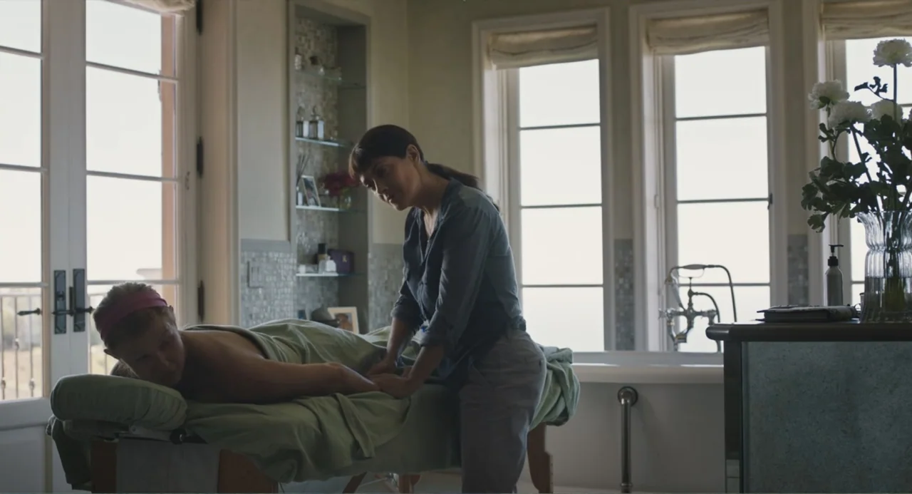 Beatriz at Dinner (2017) movie still: medium — A sunlit bathroom features large windows, a massage table, and decorative mosaic tile accents. One…